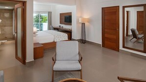 Hotellihuone, jossa on sänky, työpöytä, tuoli, televisio ja parveke, jolta on näkymä.