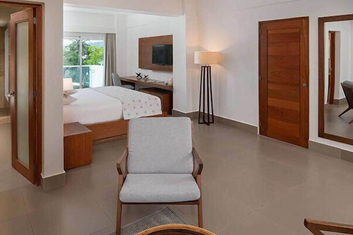 Ein Hotelzimmer mit Bett, Schreibtisch, Stuhl, Fernseher und einem Balkon mit Blick.