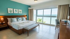 Habitación de hotel con una cama grande, un escritorio, vista al mar y obras de arte en la pared.
