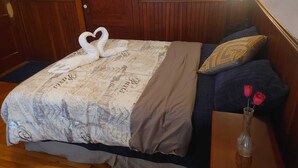 Een hotelkamer met een bed, een nachtkastje, een vaas met bloemen en een houten deur.