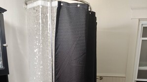 Een badkamer met douchegordijn, wastafel, toilet en raam.