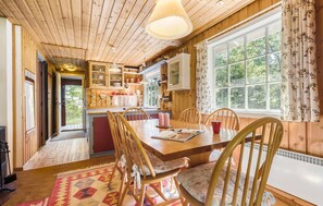 L’intérieur d’un chalet en bois chaleureux et accueillant, avec un coin repas, une cuisine et de grandes fenêtres.