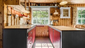Cocina de cabaña de madera con una isla central, armarios de madera y ventana con vistas a la vegetación.