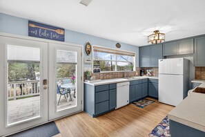 A kitchen with a view to the outside, a clock, and a sign that says 'on lake time'. - Lakefront, Water Views, Firepit | Drift and Dock (Spicewood)