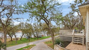 Um imóvel residencial com um acesso pavimentado, um deck de madeira e vista para um lago.