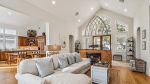 A spacious living area with a sofa, fireplace, dining table, and kitchen in the background. - Natures Canopy - Hosted by Moore AI Rentals (Fernandina Beach)