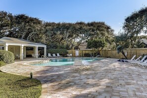 A pool area with lounge chairs, a covered seating area, and a wooden fence. - Summer Beach Cottage - Hosted by Moore AI Rentals (Fernandina Beach)