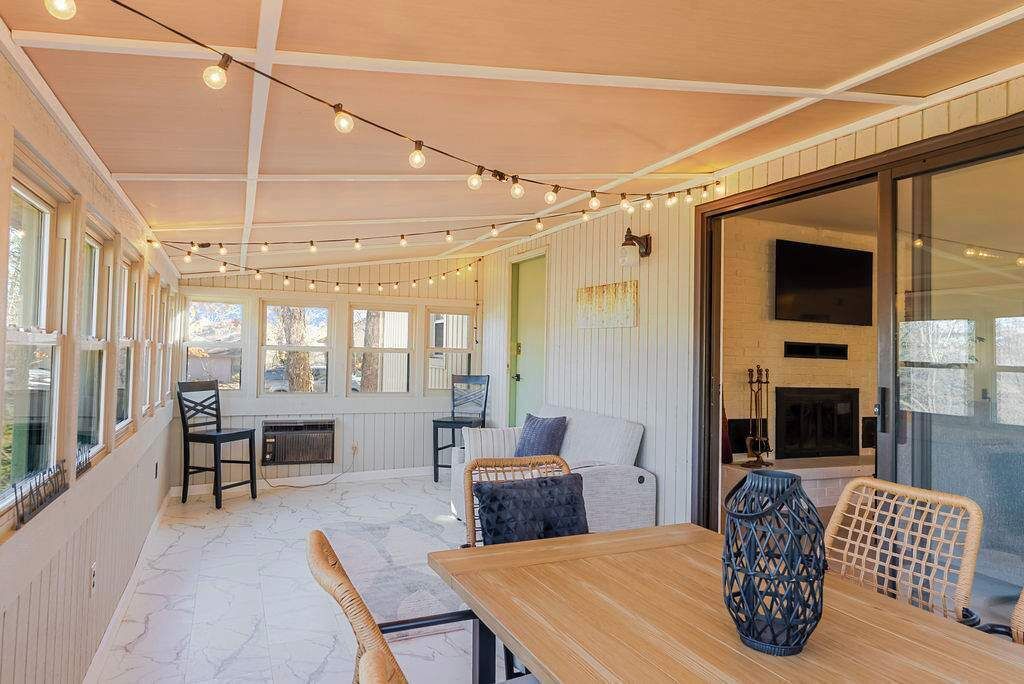 A cozy room with a wooden table, wicker chairs, a sofa, and string lights.