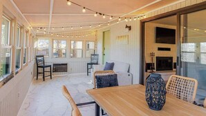 Ein gemütliches Zimmer mit Holztisch, Korbstühlen, einer Couch und Lichterketten.
