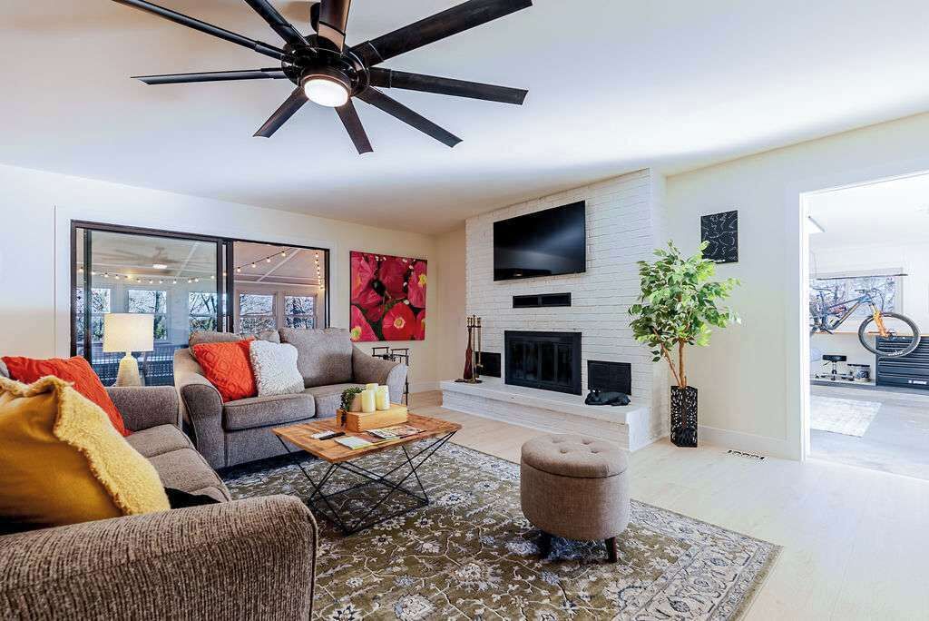 A modern living room with a ceiling fan, a fireplace, a large TV, and a sofa.