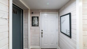 Un corridoio con una porta bianca, un quadro appeso al muro e un cartello sopra la porta.