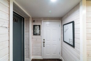 Um corredor com uma porta branca, um quadro na parede e uma placa acima da porta.