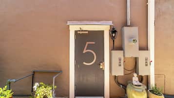 A door with the number 5, outdoor electrical boxes, and a statue on the wall.