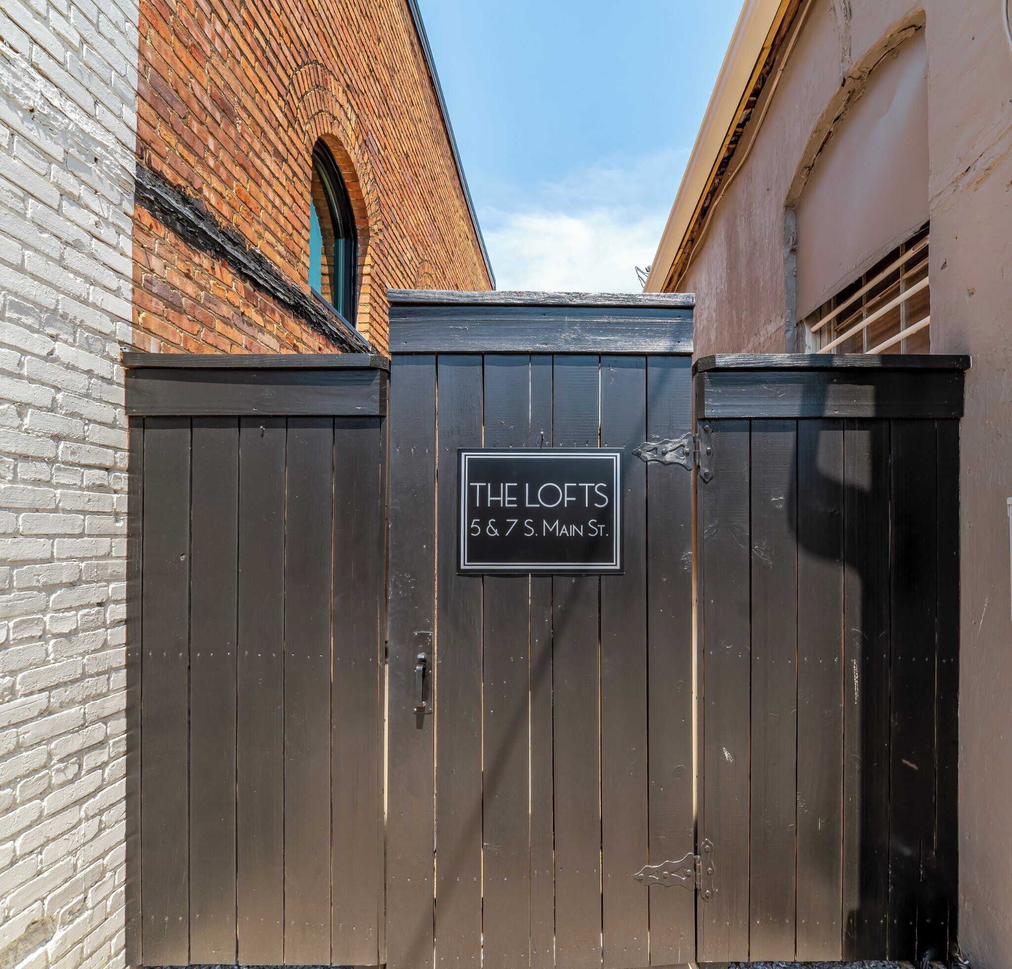 Een zwart hek met een bord waarop 'THE LOFTS 5 & 7 S. MAIN ST.' staat.