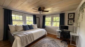 Une chambre à coucher avec un lit, un bureau, un ordinateur et un ventilateur de plafond.