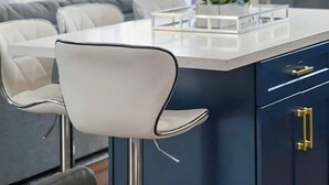 A modern kitchen with a central island, bar stools, and a chandelier.
