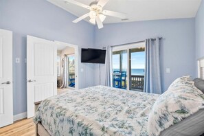 A bedroom with a bed, a ceiling fan, a TV, and a balcony with a view. - Private POOL + Stunning Ocean Views in Heart of Surf City! (Surf City)