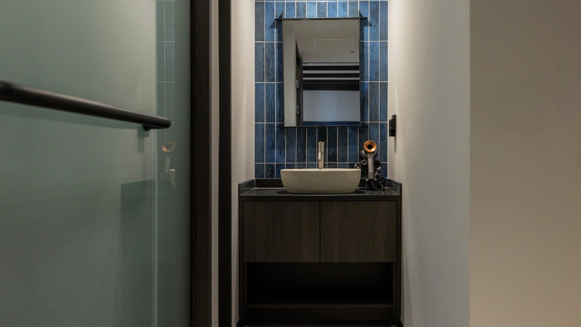 A bathroom with a glass door, a sink, a towel rack, and a mirror.