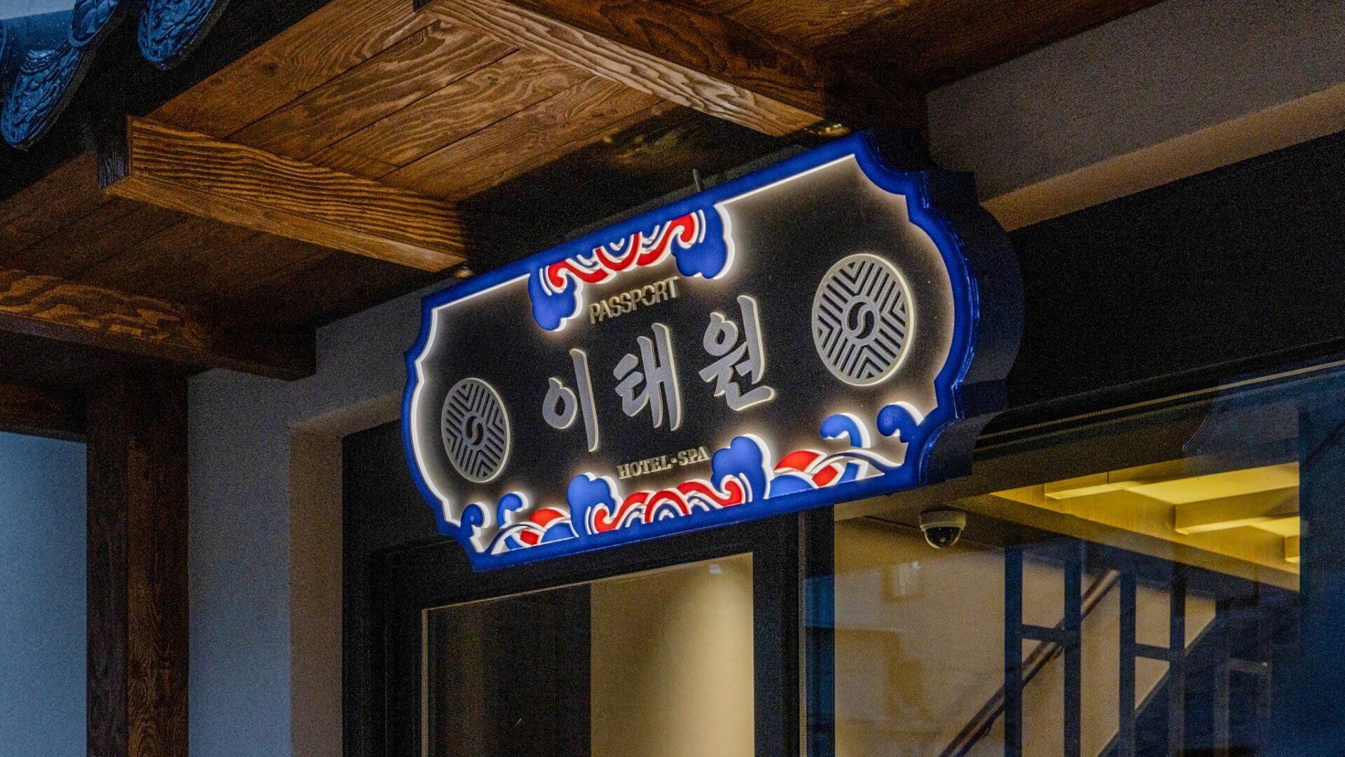 Un letrero con texto coreano y un diseño que simula un sello de pasaporte, indicando un hotel o spa.