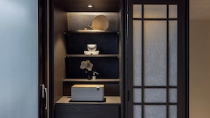 Ein traditioneller japanischer Raum mit einer Schiebetür, einem Regal mit einem Fächer, einem kleinen Tisch und einer Schachtel.