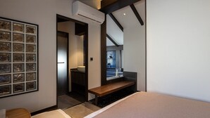 Ein modernes Schlafzimmer mit einem großen Spiegel, einem Nachttisch und Blick ins Badezimmer.
