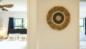 Hotellihuone, jossa on sänky, kattotuuletin ja seinälle kiinnitetty koriste-esine.