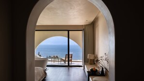 Une pièce dotée d’une grande porte en arc donnant sur un balcon avec vue sur la mer.