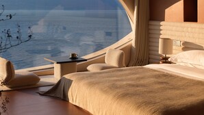 Une chambre à coucher avec une grande fenêtre en arc de cercle, un lit, une table de chevet et une lampe.