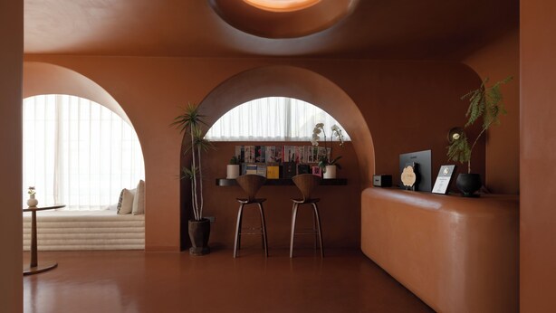 Ein modernes Interieur mit Bogenfenstern, einer Sitzecke und einer Rezeption.