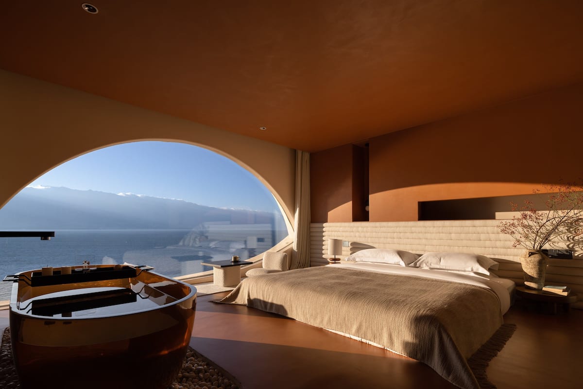 A bedroom with a large arched window, a bed, bedside tables, and a nightstand.