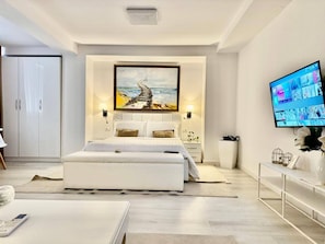 A modern bedroom with a large bed, a television, and a painting on the wall. - Leo s Garden View Apartment Cozy 1BR (Tirana)