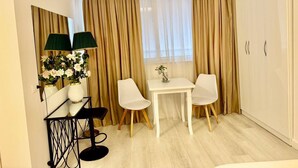 A hotel room with a bed, a desk with two chairs, a small table, a mirror, and a wardrobe. - Leo s Garden View Apartment Cozy 1BR (Tirana)