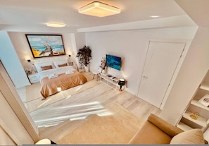 A modern bedroom with a bed, bedside tables, a TV, and a door. - Leo s Garden View Apartment Cozy 1BR (Tirana)