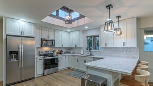 A modern kitchen with a skylight, stainless appliances, and a marble island. - Fountain Hills Splendor: One Story, Pvt Pool, Putting Green, Fire Pit, Near Hiking/Biking & Golf (Fountain Hills)