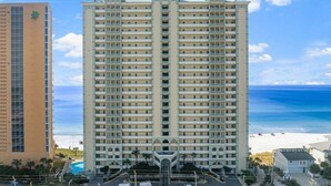 Un hotel de gran altura con varios balcones, una piscina y vistas a la playa.