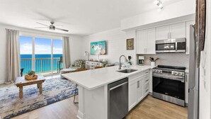 Una cocina moderna con armarios blancos, una isla central, horno integrado y microondas.