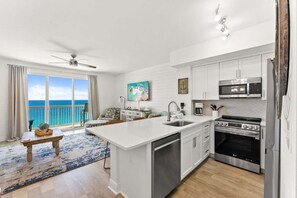 A modern kitchen with white cabinetry, a central island, a built-in oven, and a microwave. - 🌴 New Luxury Gulf-Front Escape | Fully Remodeled with Stunning Views 🌊 (Panama City Beach)