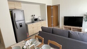 A compact living space with a kitchenette, a sofa, a dining table with chairs, and a television.