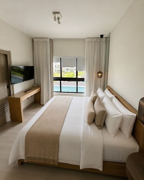 Une chambre d’hôtel moderne dotée d’un grand lit, d’une télévision à écran plat, d’un bureau et offrant une vue sur une piscine.