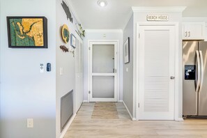A hallway with a framed map, a door labeled 'BEACH HOUSE,' and a stainless steel refrigerator. - Blind Pass Condos at Bowman's Beach E202 on beautiful Sanibel Island (Sanibel)