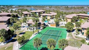 Un barrio residencial con varias casas de dos pisos, una cancha de tenis y una piscina.