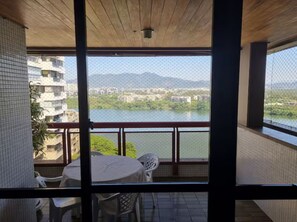 Un balcon avec une table et des chaises, donnant sur une étendue d’eau et des bâtiments.