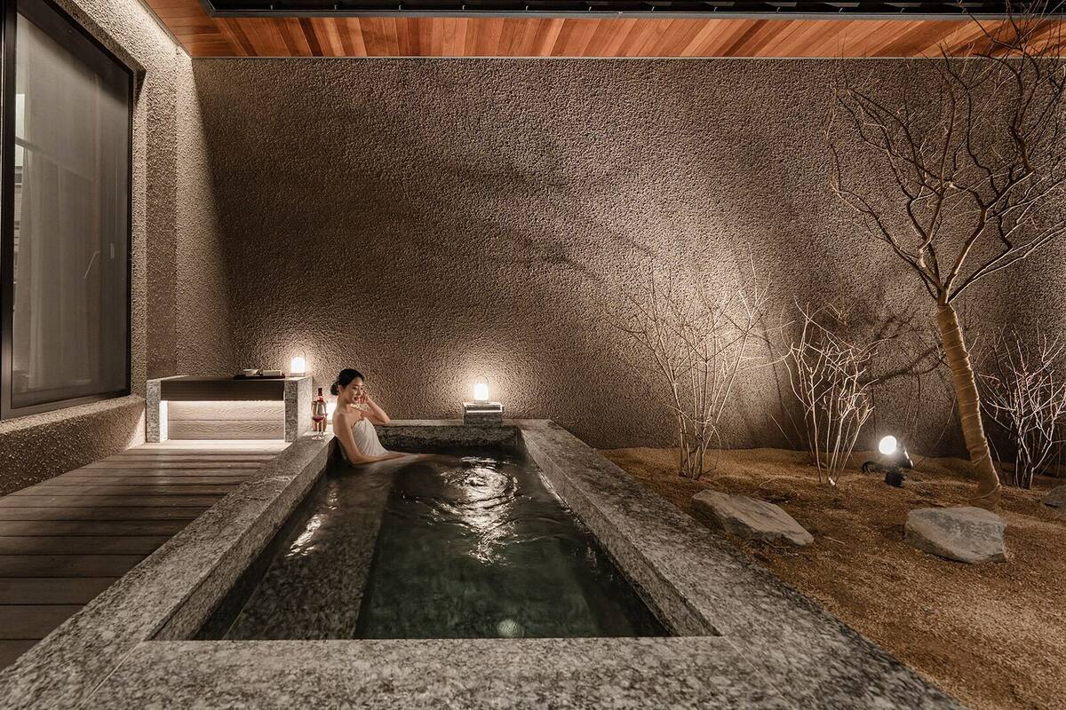 Un espace bien-être comprenant un jacuzzi, une terrasse en bois et des murs en pierre.