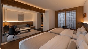Een moderne hotelkamer met een bank, twee bedden, een bureau en uitzicht op een traditionele Japanse schermen.