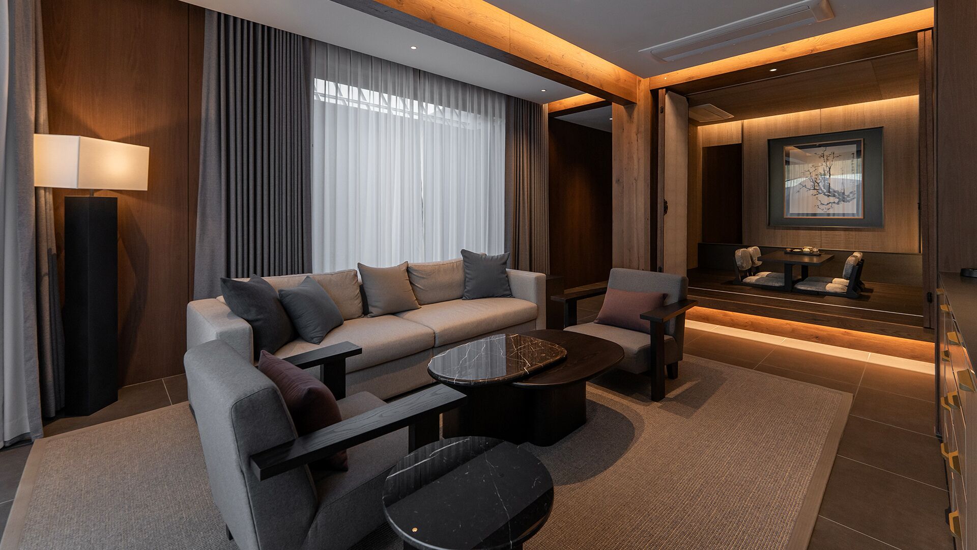 Een moderne hotelkamer met een bank, fauteuils, een salontafel en een eethoek.