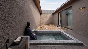 Uma área de spa com uma banheira de hidromassagem, um deck de madeira e uma parede de pedra.