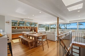 Een ruime woonkamer met een houten eettafel, een bank en een balkon met uitzicht.