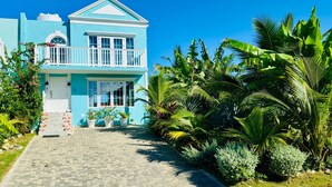 Un bâtiment à deux étages doté d’un balcon, entouré d’une végétation tropicale luxuriante.
