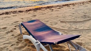Une plage avec un seul transat sur le sable.