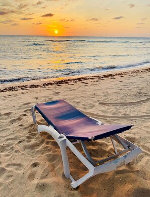 A beach with a single sun lounger on the sand.